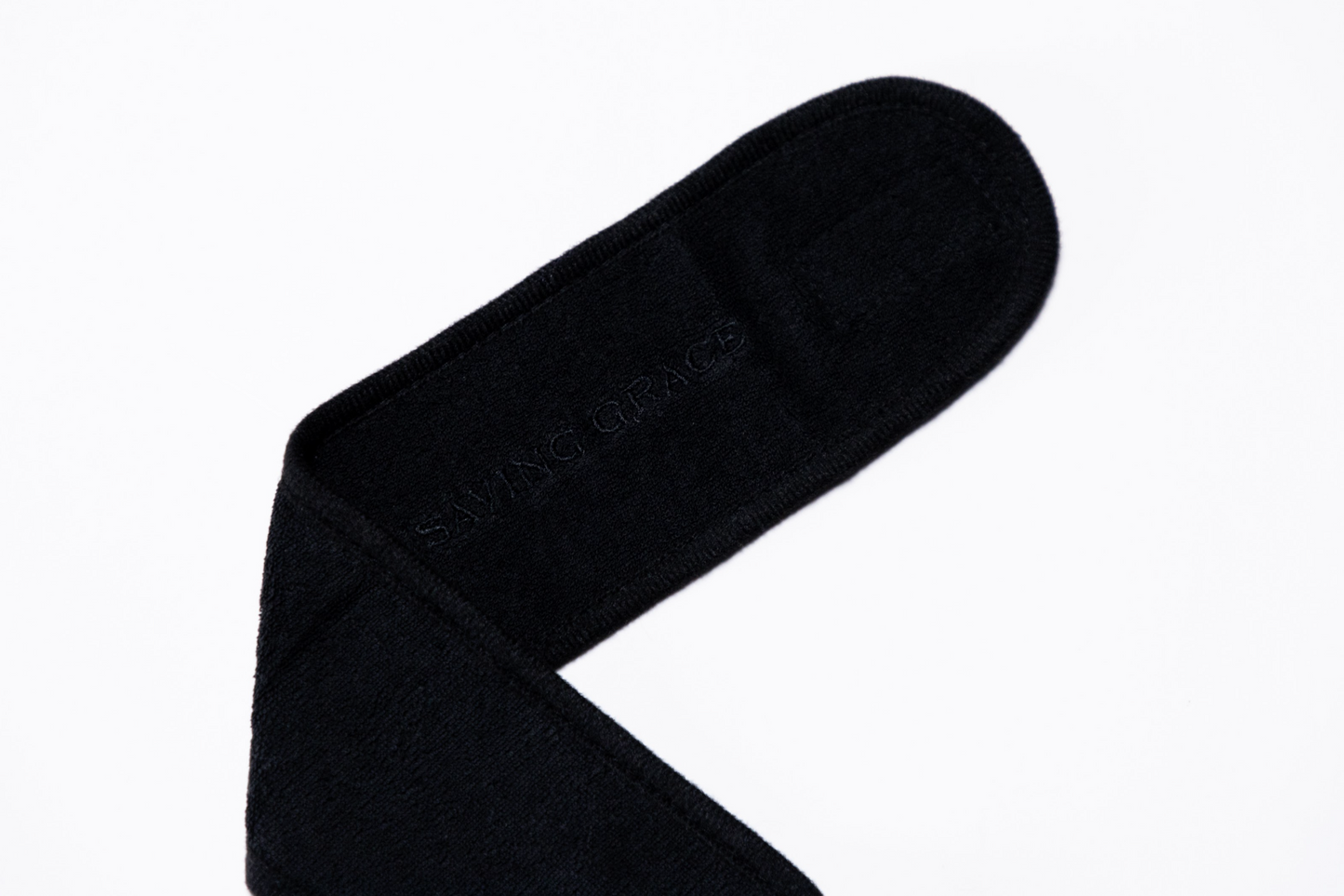 Soft terry cloth spa headband crafted for comfortable, hands-free skincare application logo detail