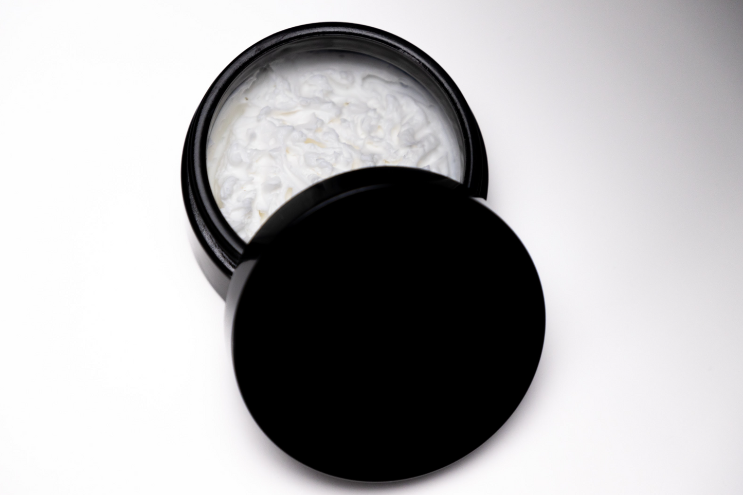 black UV glass jar with whipped body butter ingredients, cocoa, sal, mango butter